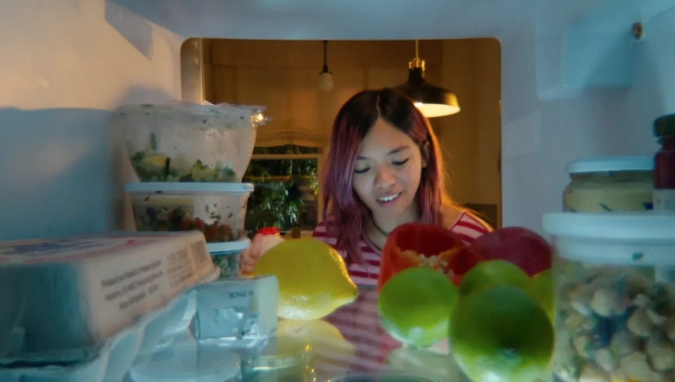 A lady in front of a fridge. 